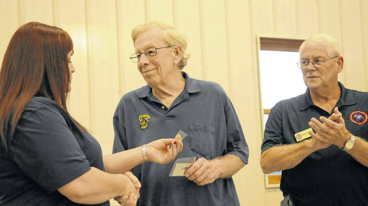 Steve Gore, center, accepts a pin and a card from Indiana Volunteer Firefighters Association 17B District Chairman Heather McGlocklin, left, for his 50 years of service as a firefighter, as 17B District public relations representative Steve Nolan looks claps. Gore accepted his award during the monthly IVFA meeting on Sept. 11 at the Brown County (Nashville) Volunteer Fire Department. Gore has been a firefighter with the Nashville department for 35 years.  Suzannah Couch | The Democrat
