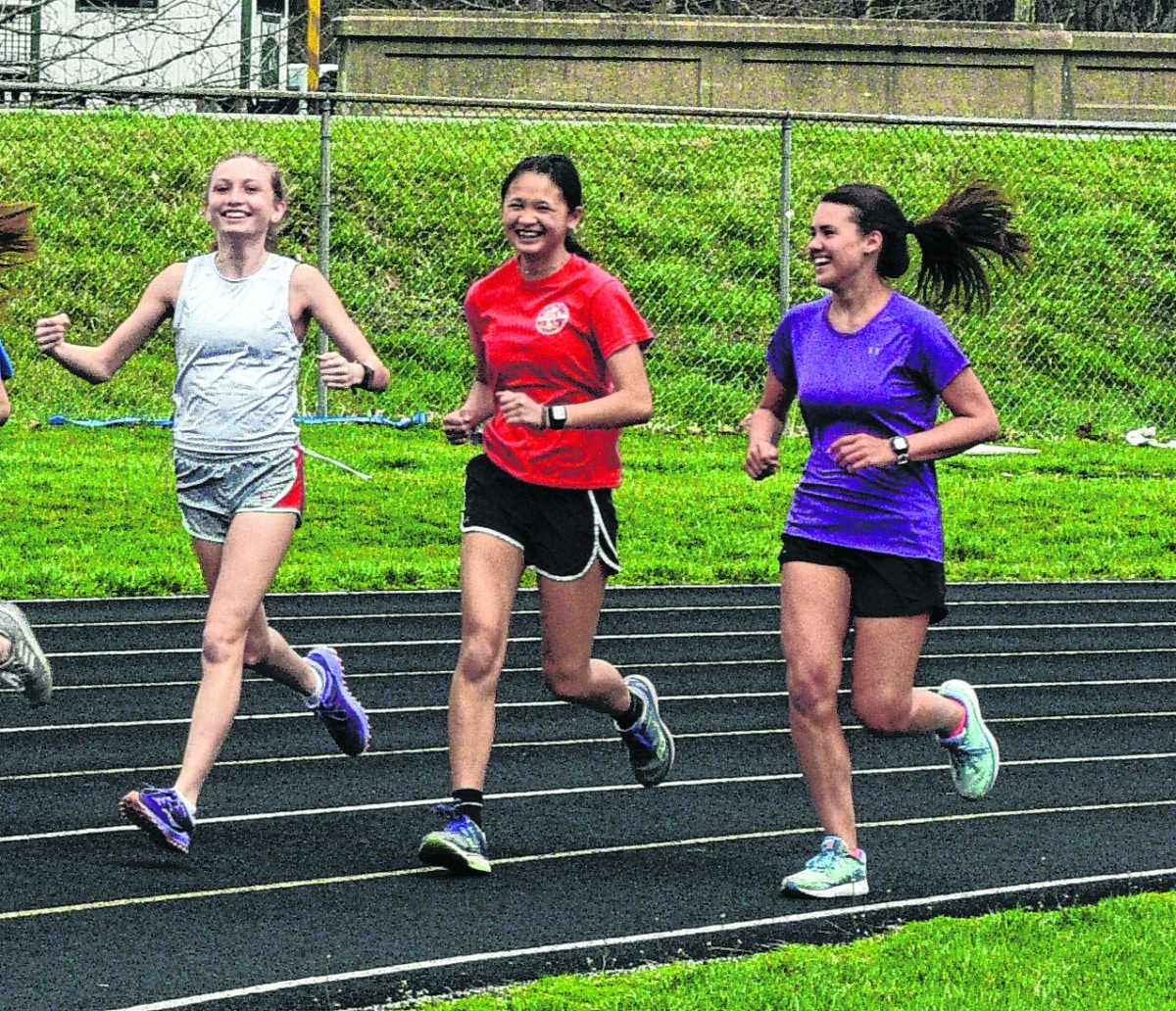 Distance runners Hadley Gradolf, Eme Koester and Lexie Austin train on the Brown County High School track on March 26. | Kevin Roush