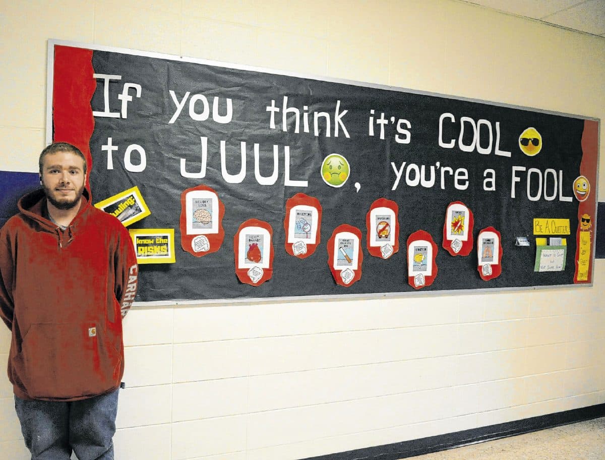 Brown County High School senior Cooper Olmsted poses for a photo next to an anti-vaping bulletin board in the school. Olmsted recently spoke to health classes about the dangers of vaping and how vaping made him sick, causing him lung damage. Olmsted no longer vapes and hopes that sharing his story with his classmates will help others quit vaping before they get sick. Suzannah Couch | The Democrat